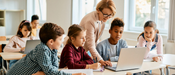 Teacher on laptop with group of students