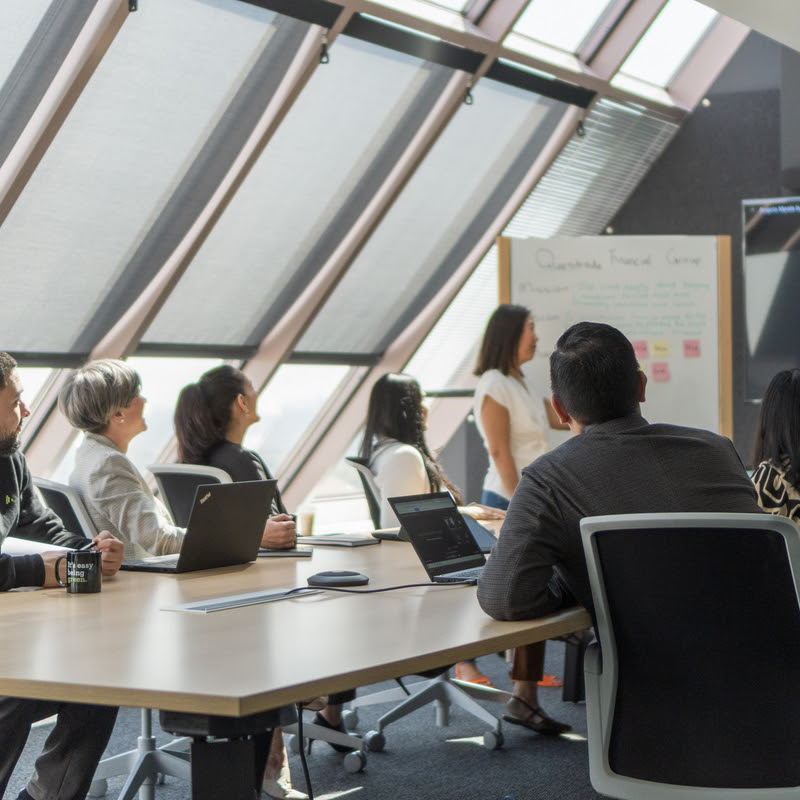 Employees sitting at a meeting desk watching a presentation