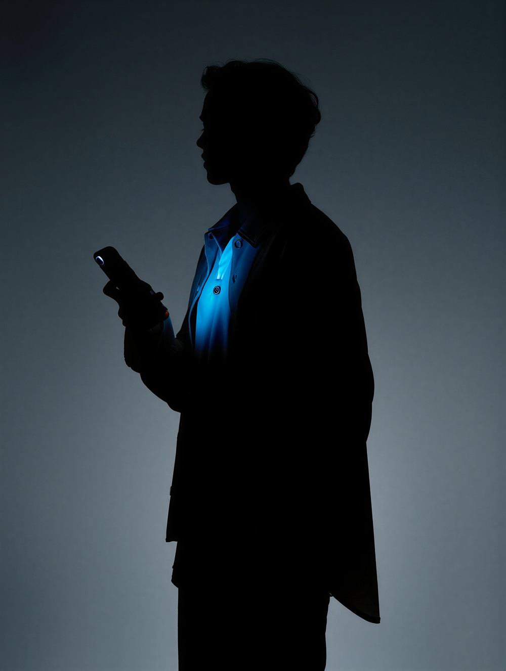 man standing in the dark with his phone