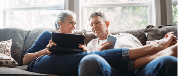 Couple sitting on couch looking at tablet